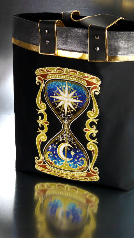 Decorative bag with a machine embroidery hourglass design featuring celestial elements.