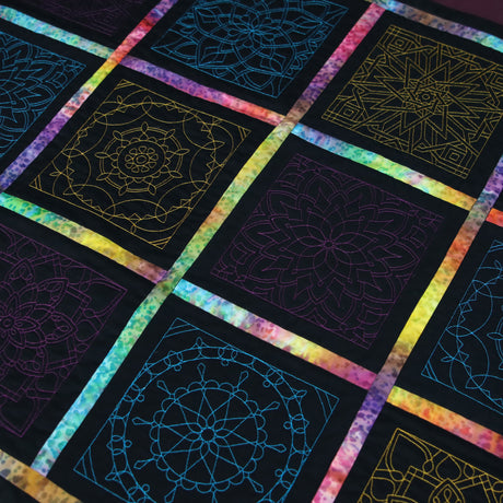 Quilt with machine embroidered geometric patterns on a black background