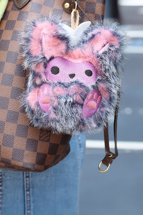machine embroidery monster plush on a purse with a grey background