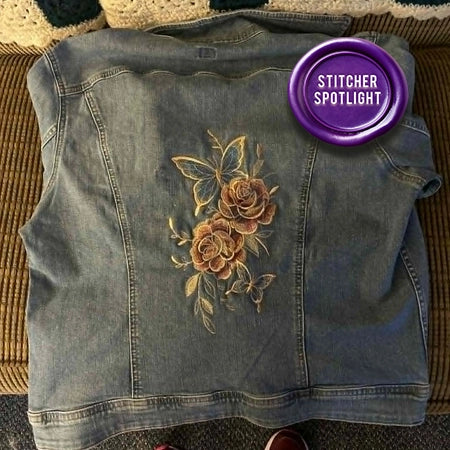 Denim vest with floral machine embroidery design on a textured surface, featuring a 'Stitcher Spotlight' label.