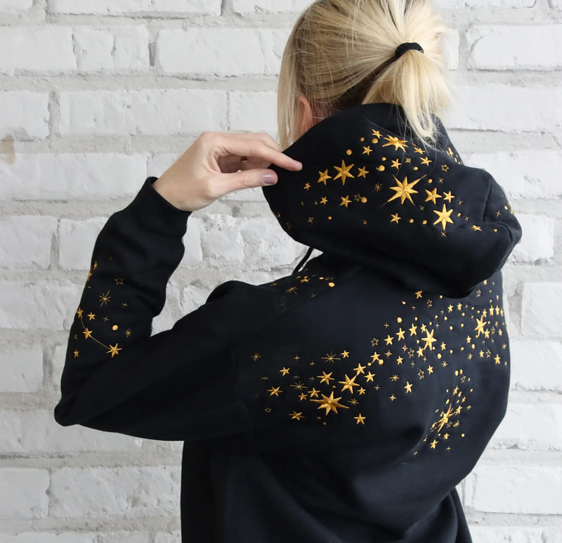 A person wearing a machine embroidery star design on a black sweatshirt by white background