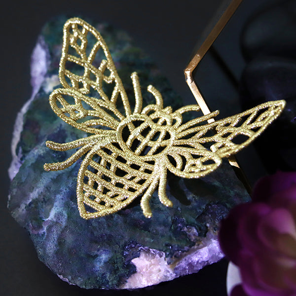 Gold machine embroidered lace butterfly on a dark background