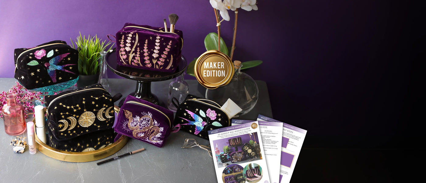 A styled product display of machine embroidered zip pouches in black and purple, arranged on a gray tabletop with a purple backdrop. A gold circular badge reads 'MAKER EDITION'.