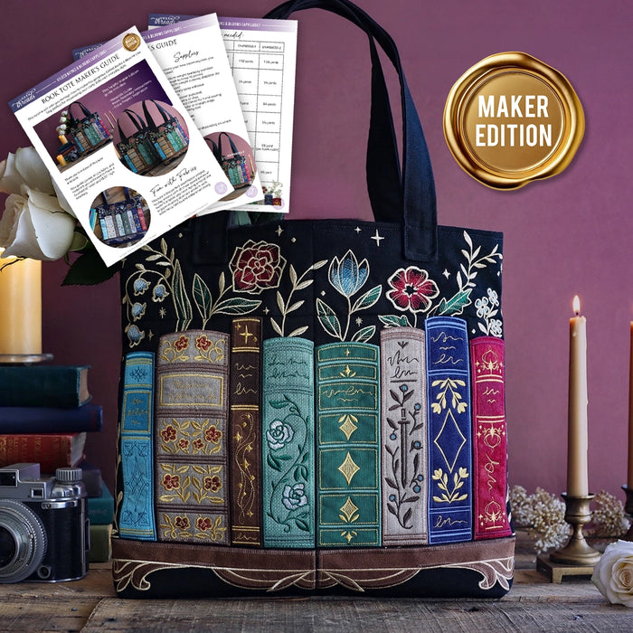 Decorative tote bag with machine embroidered applique book design on a wooden surface against a purple wall. Wax seal styled gold icon reads "maker edition".