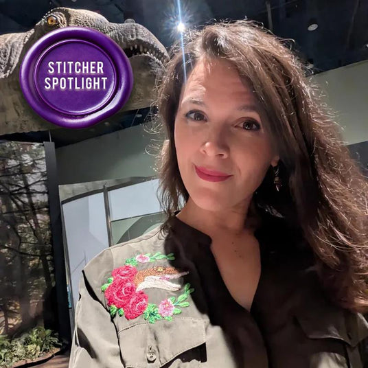 Woman wearing a dress with a dinosaur machine embroidery design, with 'Stitcher Spotlight' badge in the corner.