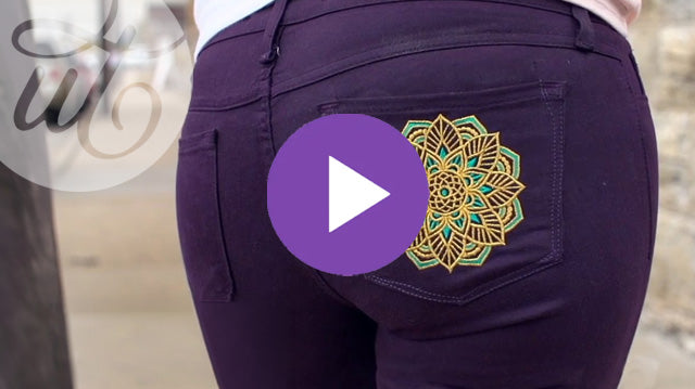 Purple pants with a decorative machine embroidered pocket on a blurred background