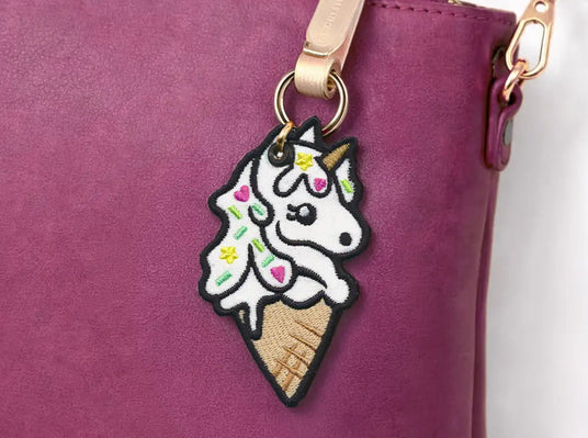 Machine embroidery unicorn ice cream cone keychain attached to a purple bag.