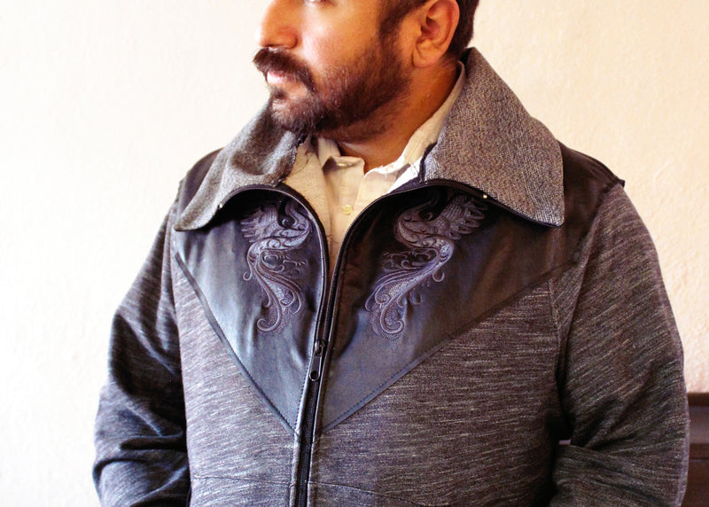Man wearing a detailed jacket with machine embroidery birds on a plain background
